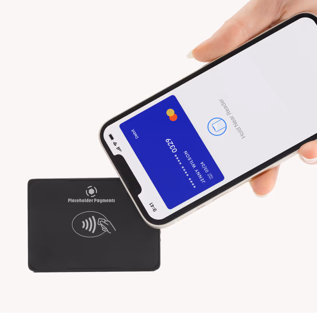 Hand holding a smartphone displaying a digital debit card near a black contactless payment reader.