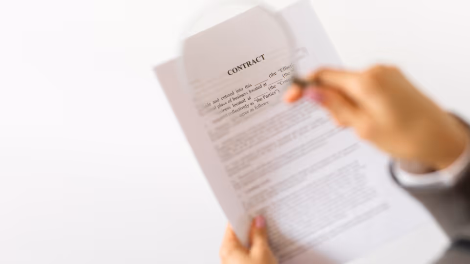 A person holding a magnifying glass over a contract