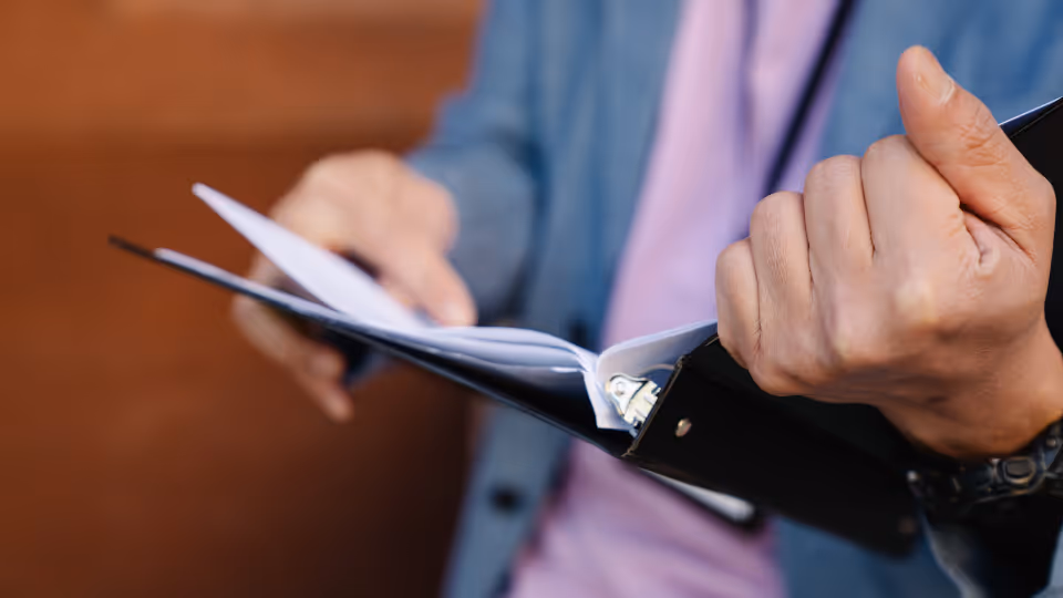 A person in a suit holding a binder