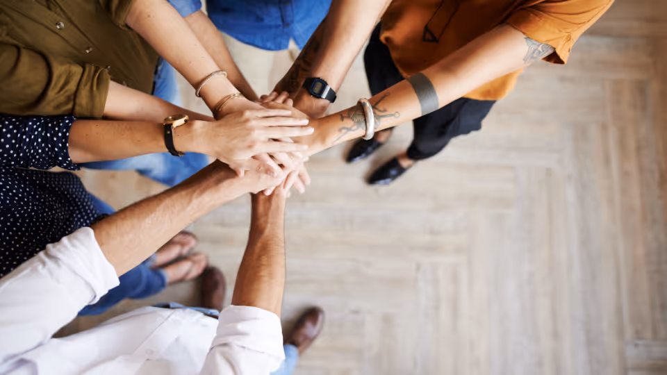 Alt text: A group of people putting their hands together in a circle