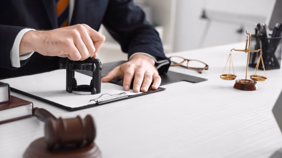 Alt text: A person in a suit holding a gavel in front of a desk