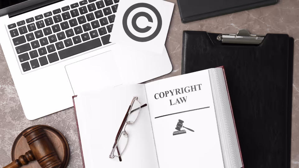Alt text: A book titled Copyright Law on a desk with a laptop, glasses, and a clipboard