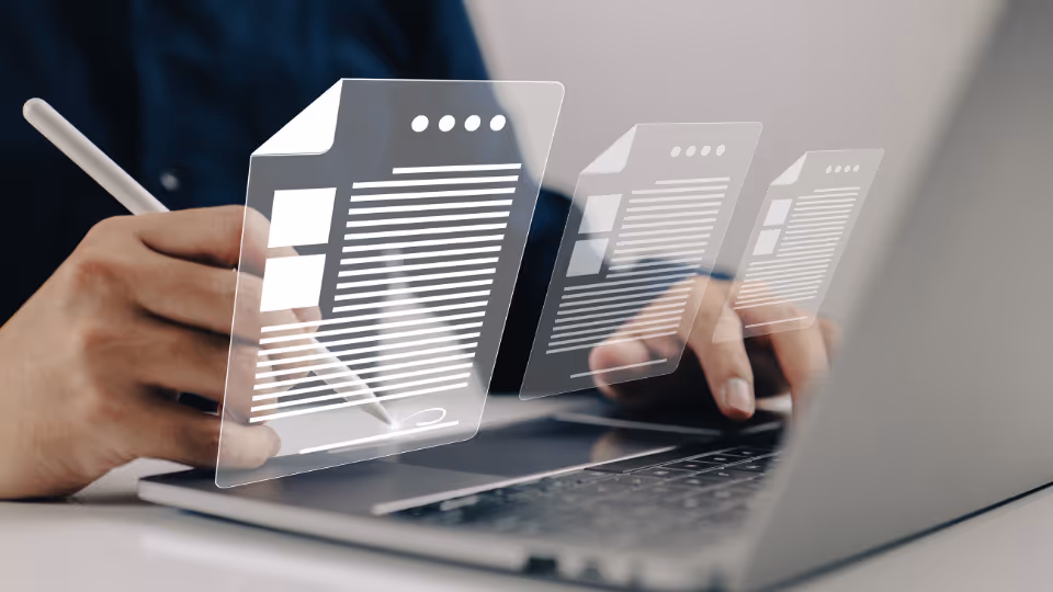 Alt text: A person working on a laptop with documents superimposed on the screen
