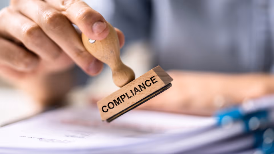 A person using a rubber stamp with the word "compliance" on it