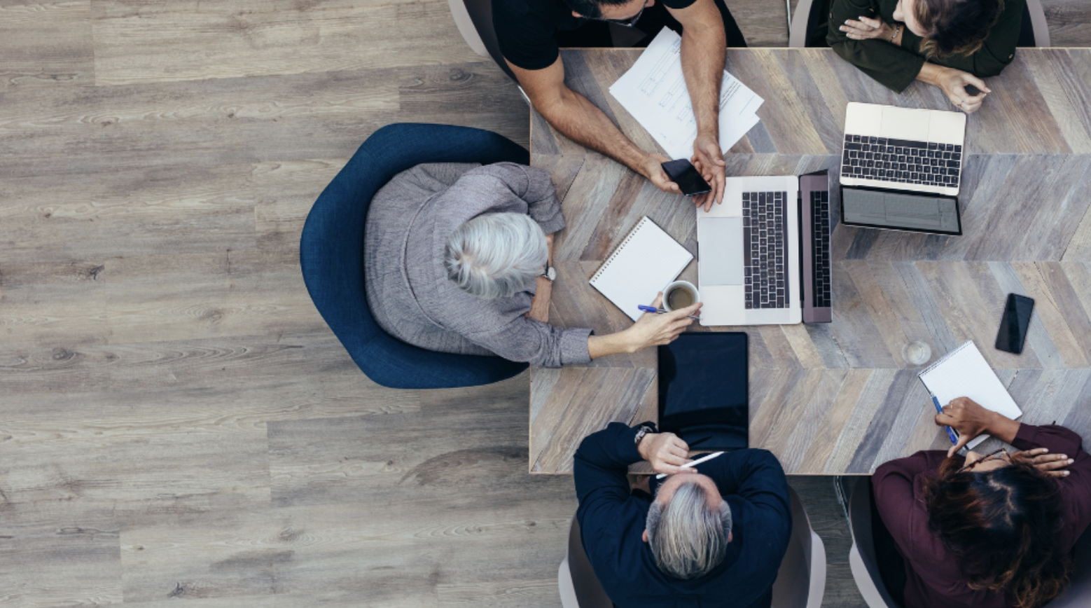 a group of people sitting around a table with laptops