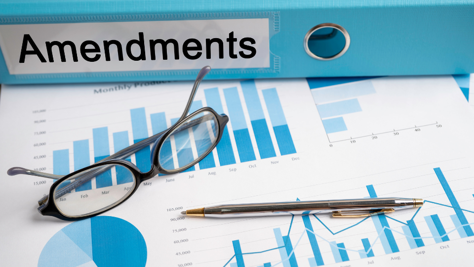 Alt text: A binder used for managing contract amendments, with a pen and glasses on top