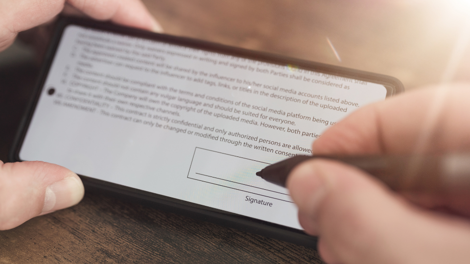 Alt text: A person using a smartphone sign an electronic signature