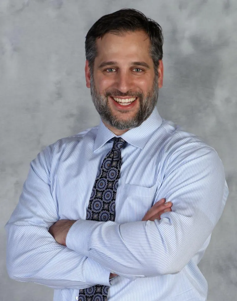 A man in a dress shirt and tie posing for a picture