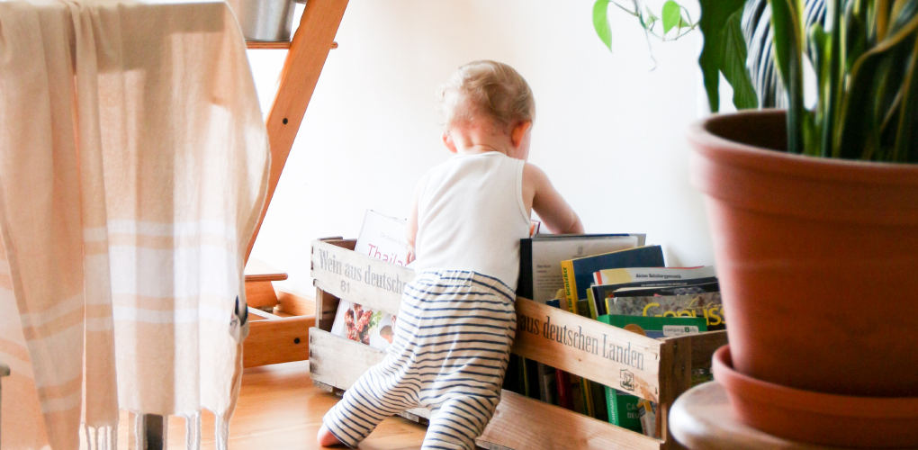 Toddler looking through a pile of books