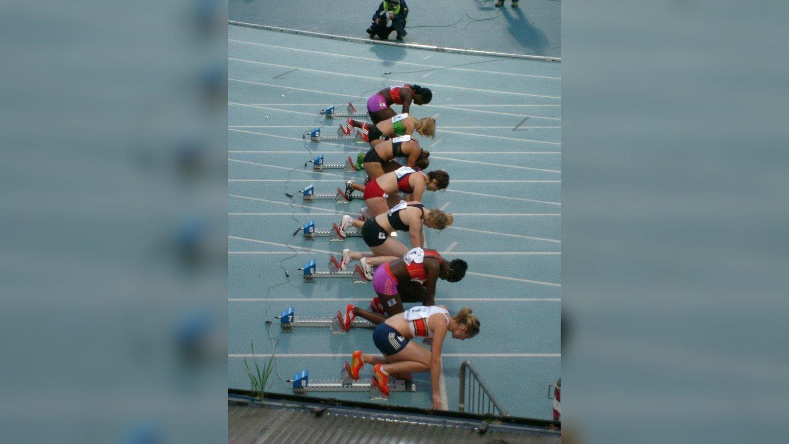 Female hurdlers aligned in starting blocks on a track, representing precision matching for athlete influencer campaigns.