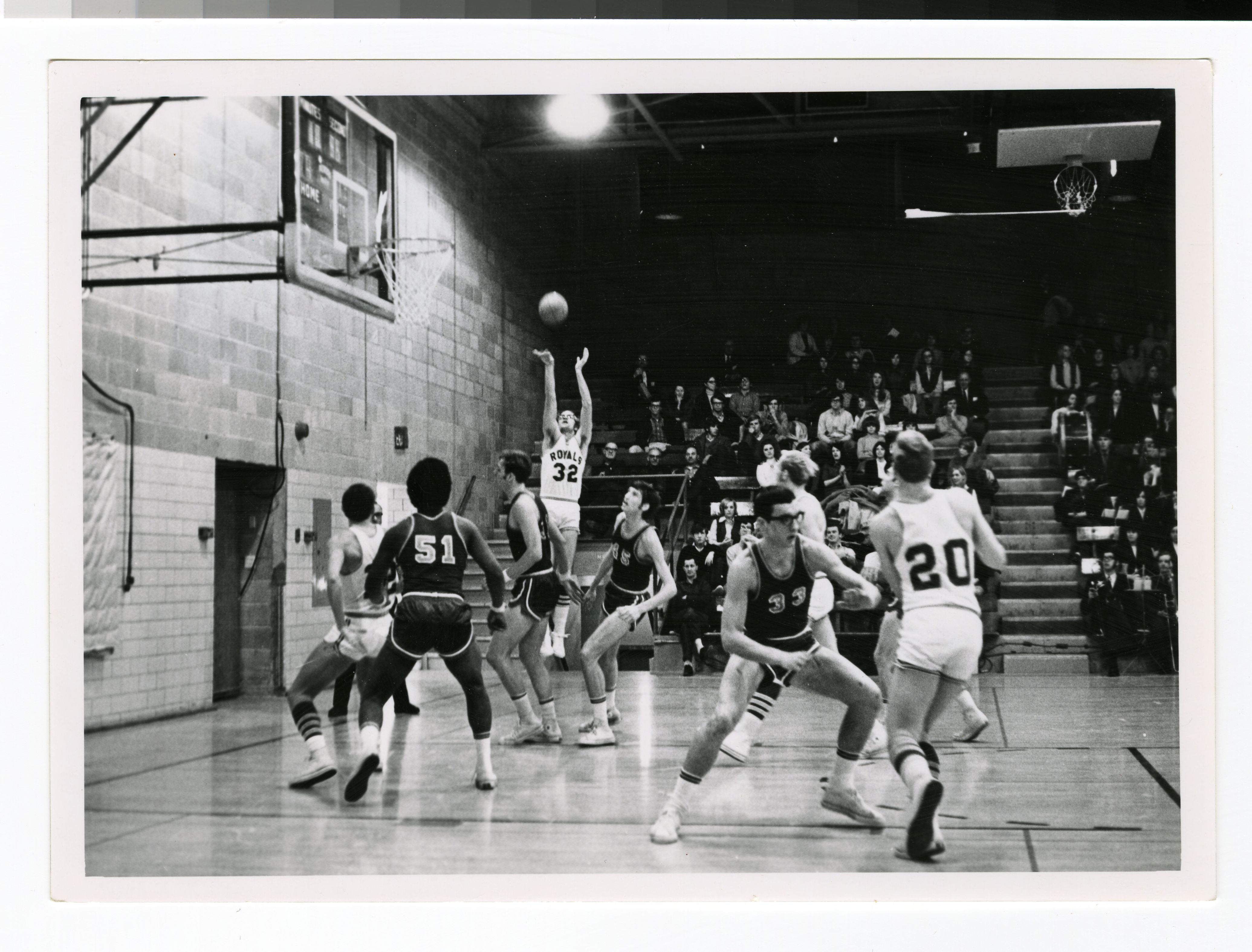 College basketball player shoots while teammates and a crowd look on, representing timely athlete influencer moments and audience attention.