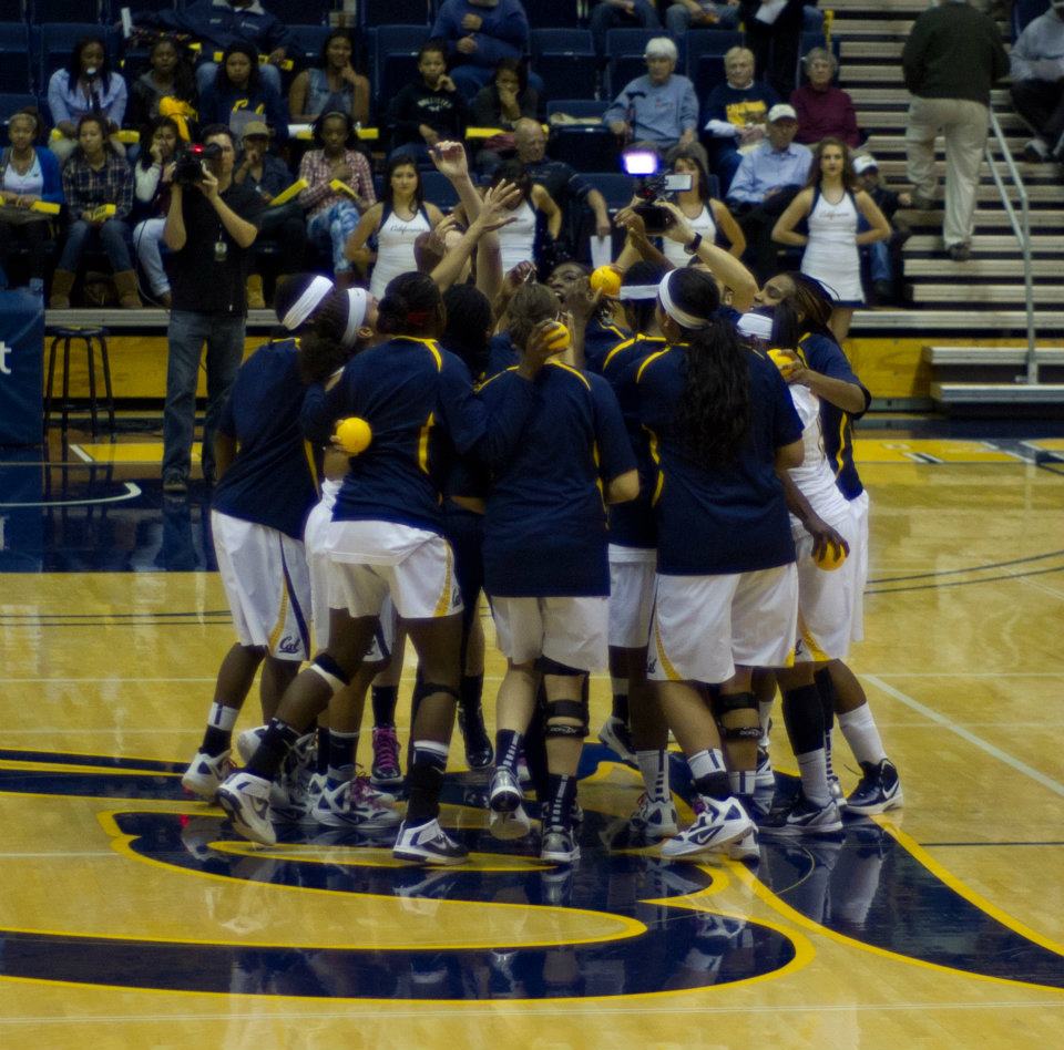 College basketball athletes huddle before a game, representing athlete ambassador networks and community trust.