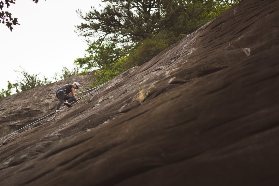 Rock climber moving up a low-angle granite slab on a roped route