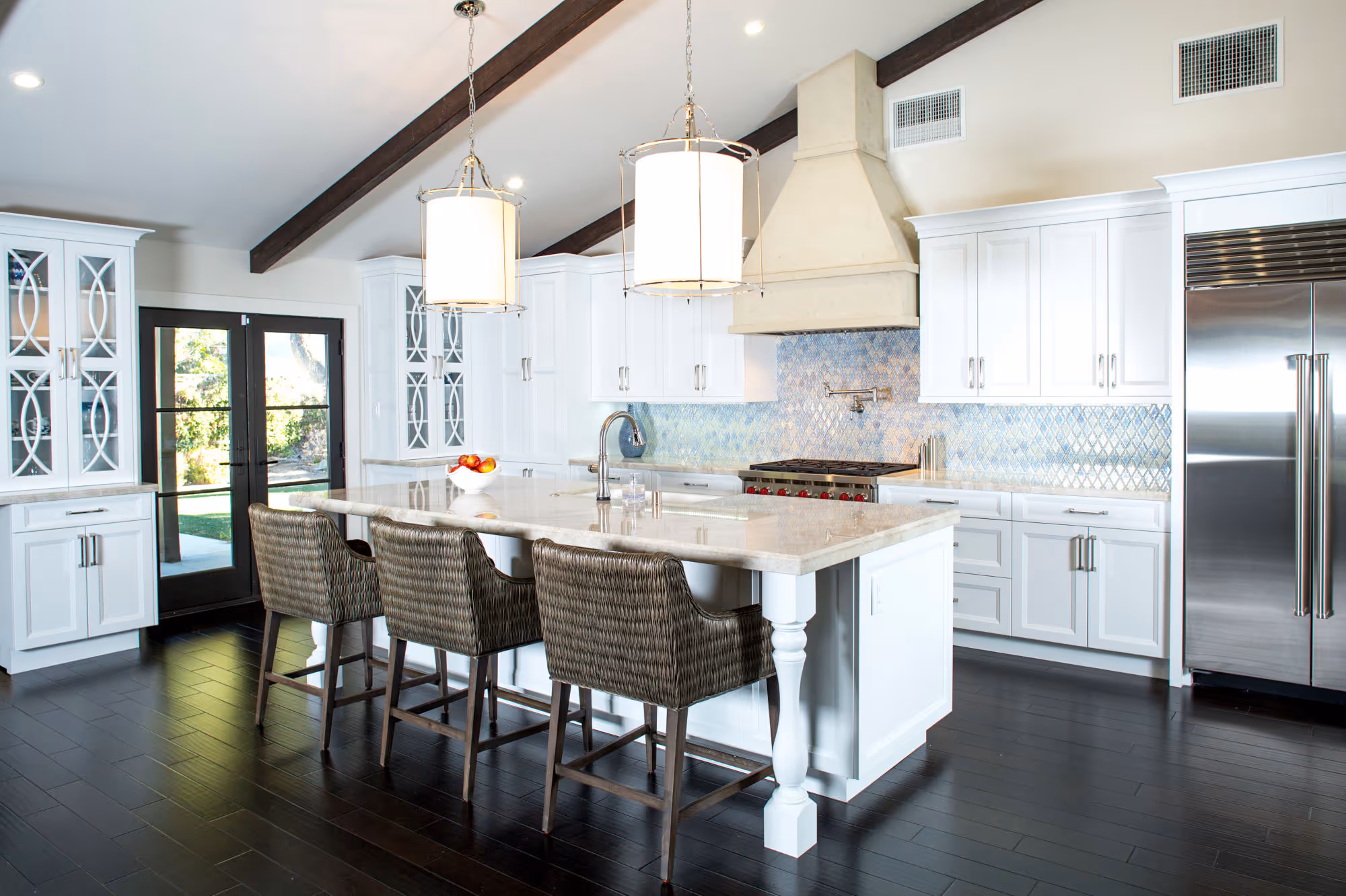 Santa Barbara styled white kitchen, mullion cabinets, large island with quartzite beige countertops.