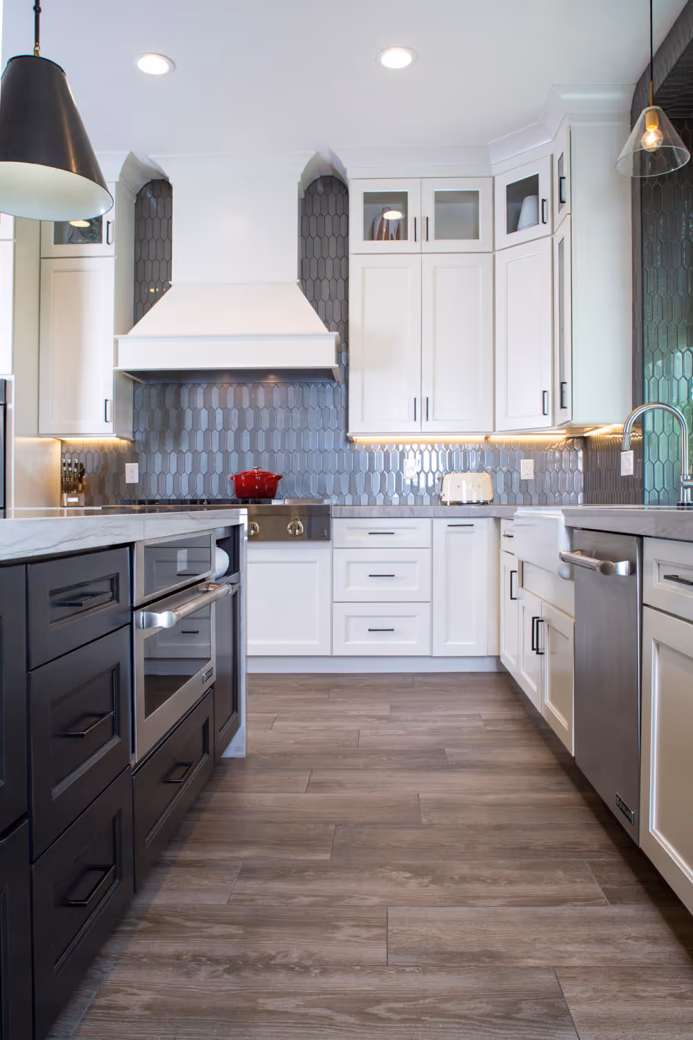White kitchen with espresso island cabinet, metal cone shaped bronze pendent, wood wrapped hood.