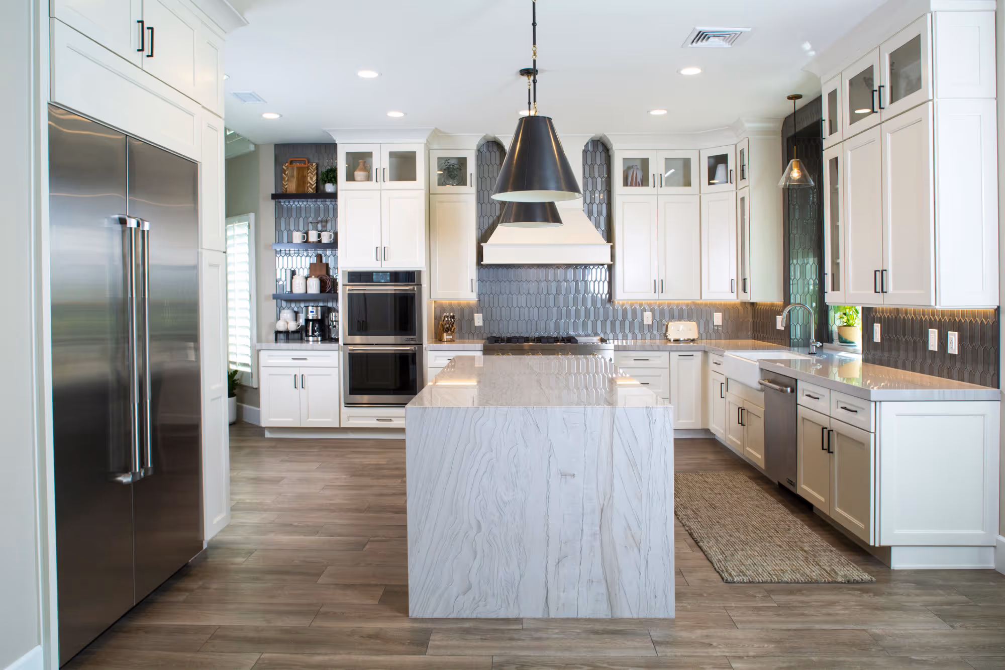New white kitchen with stainless steel appliances and quartzsite waterfall island.