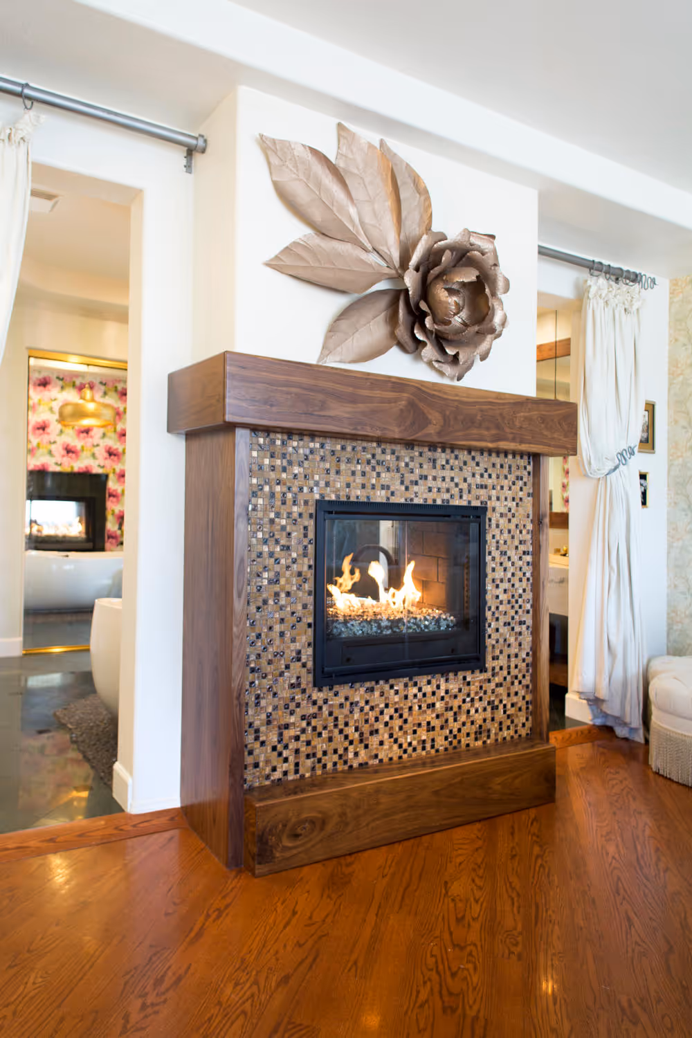 Master bedroom fireplace with wood mantel, mosaic tile suround and metal flower decor above.  