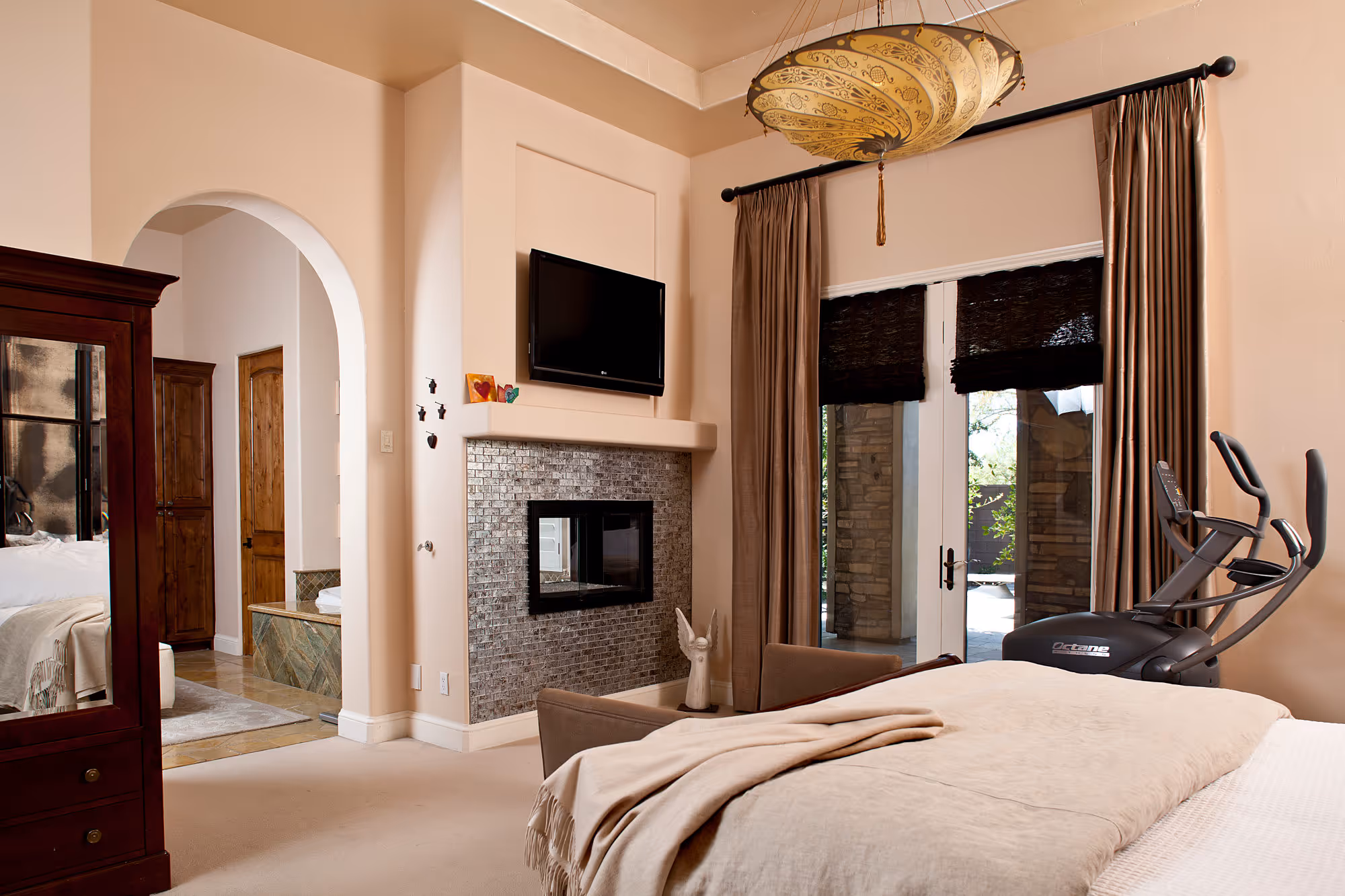 Spanish styled master bedroom with fireplace and large french doors to the garden.