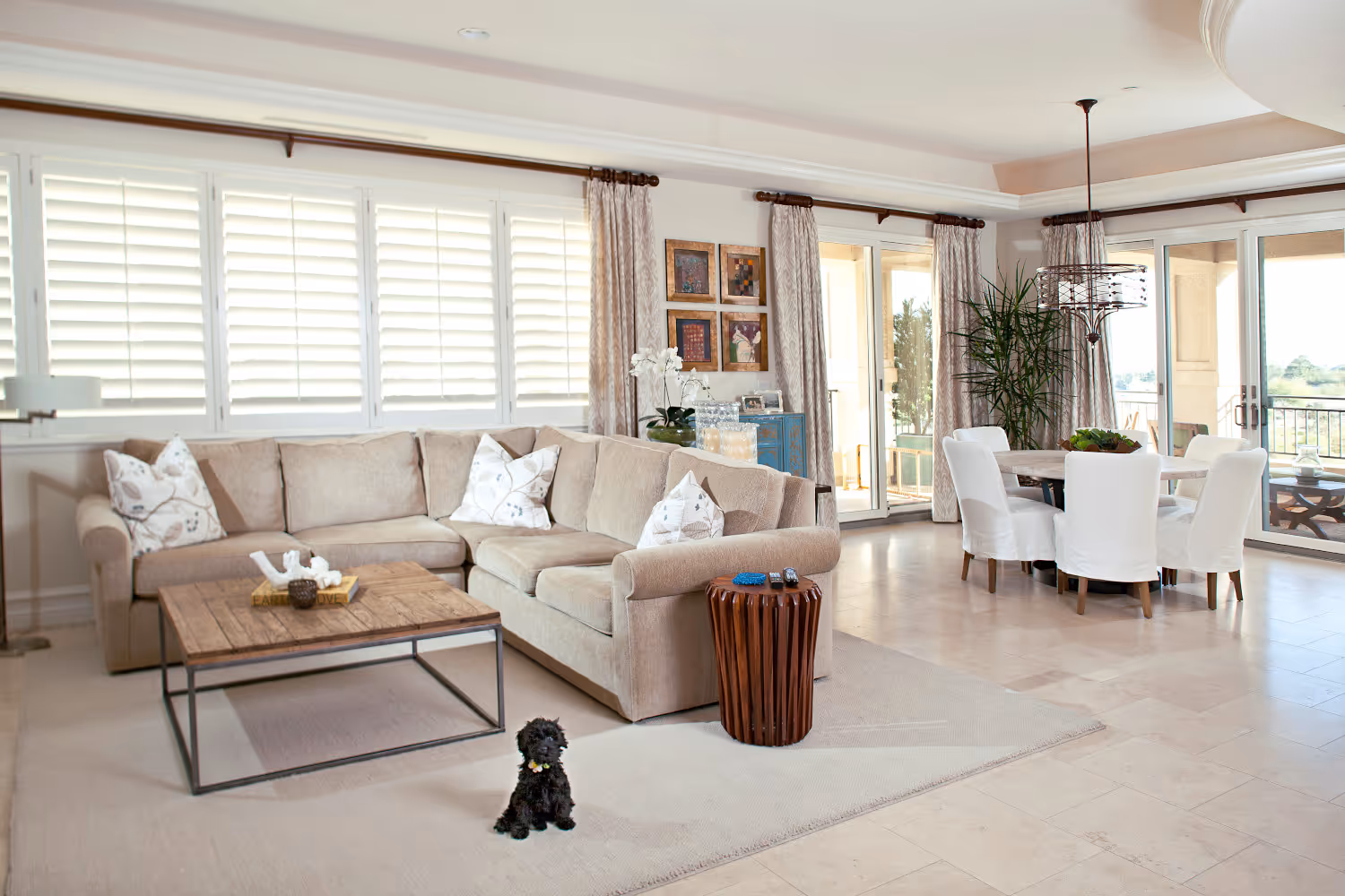 Open space bright family room and dining room combo, with cream travertine flooring.