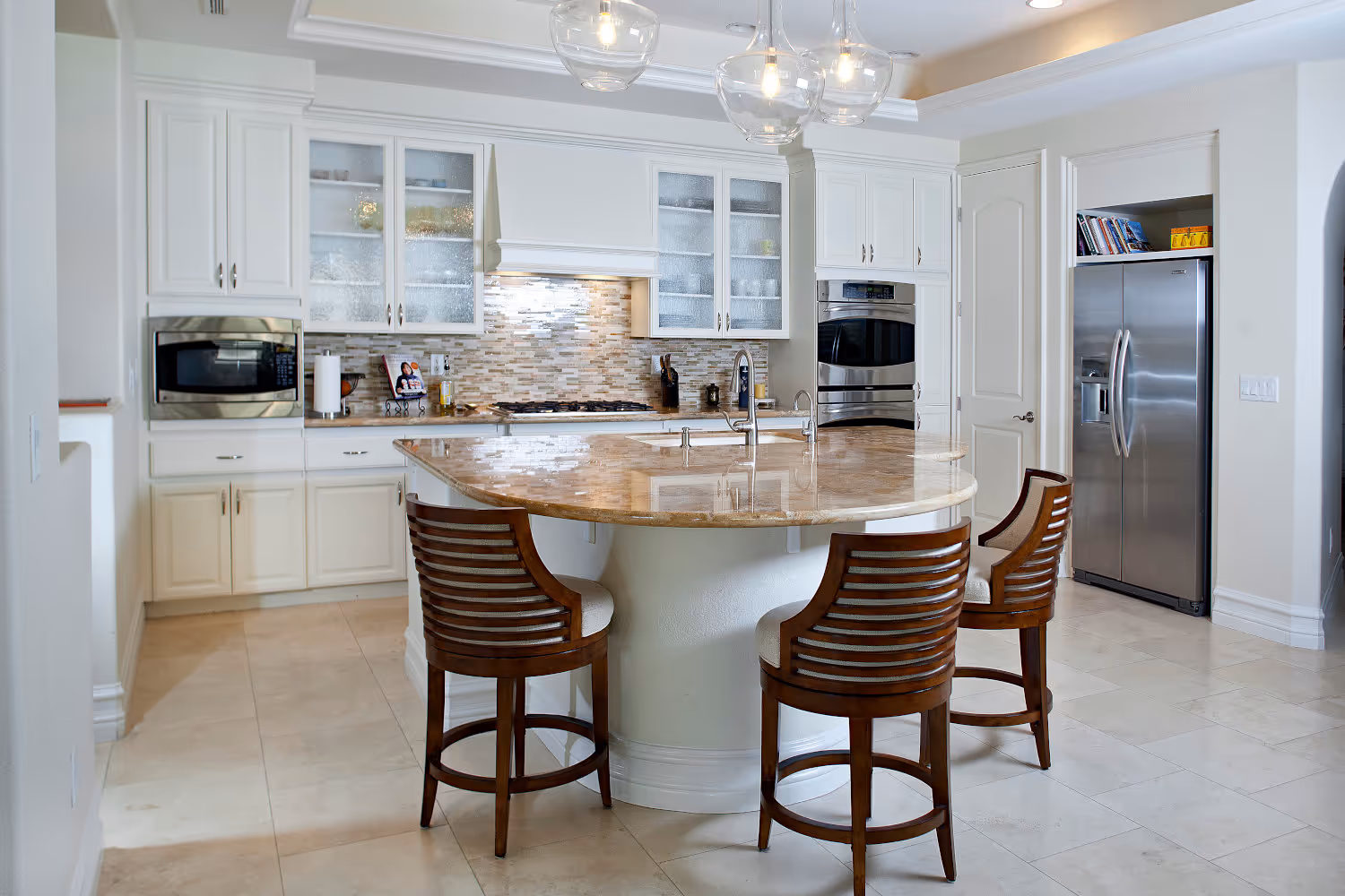 Traditional kitchen, white cabinets, travertine countertops, glass backsplash, wood counter stools.