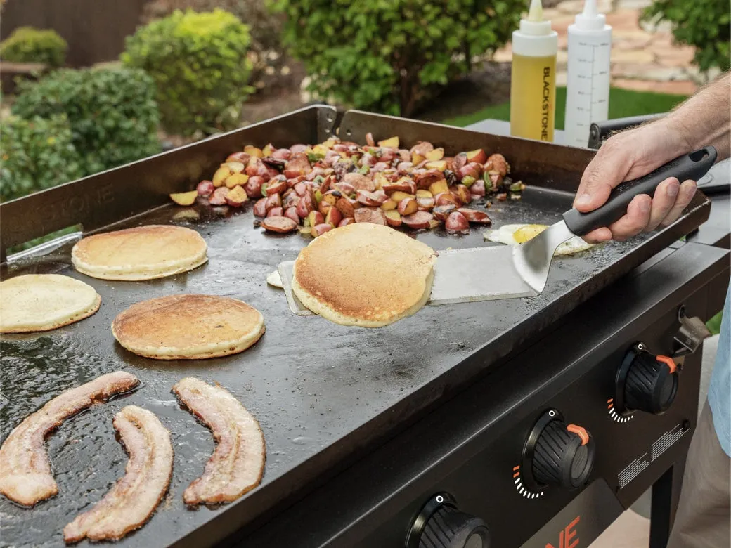 Pancakes, bacon, and breakfast potatoes cooking on a Blackstone 36-inch griddle outdoors