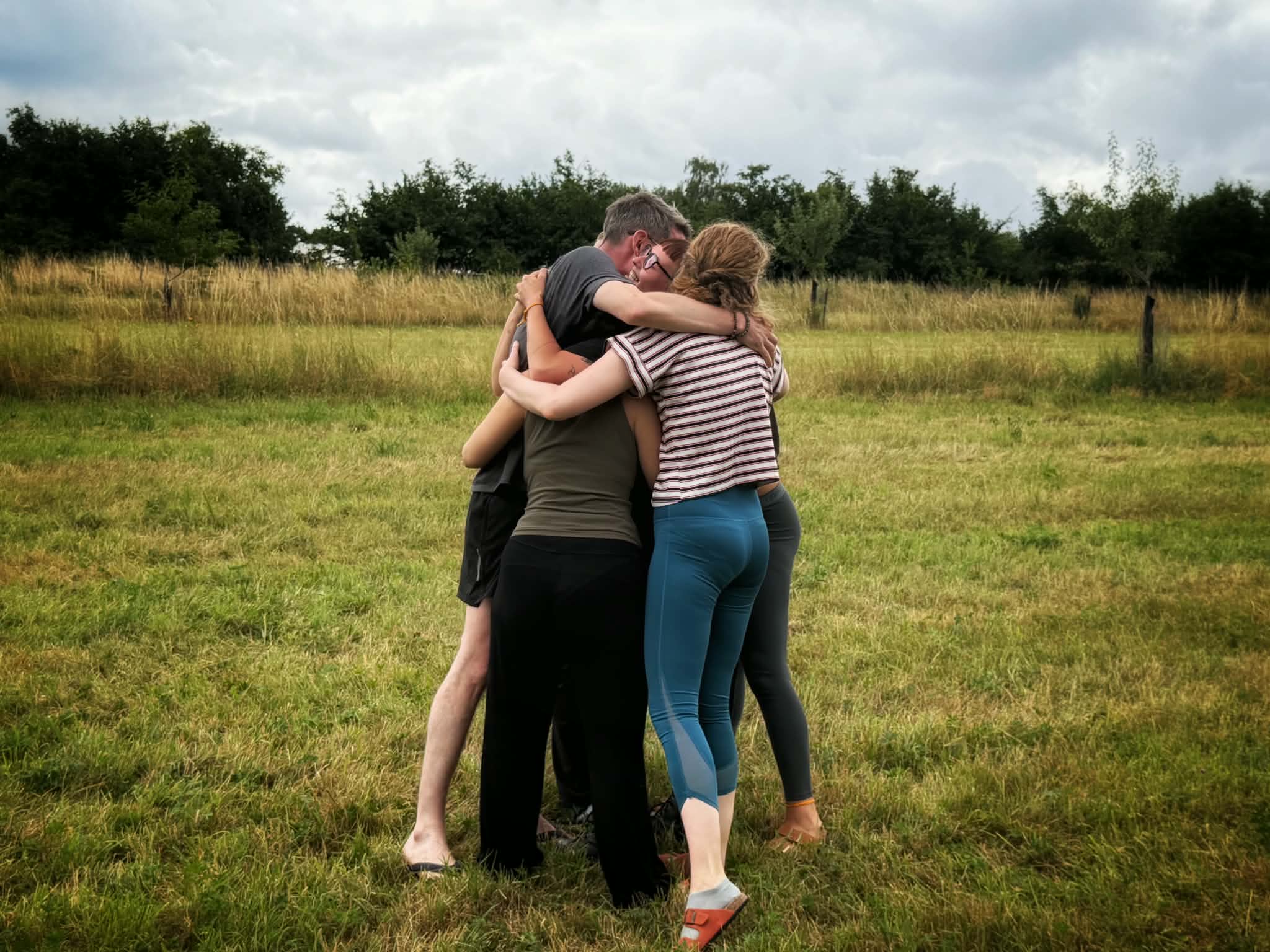 Participant.es de la retraite Animae réuni.es dans un câlin de groupe, dans un champ