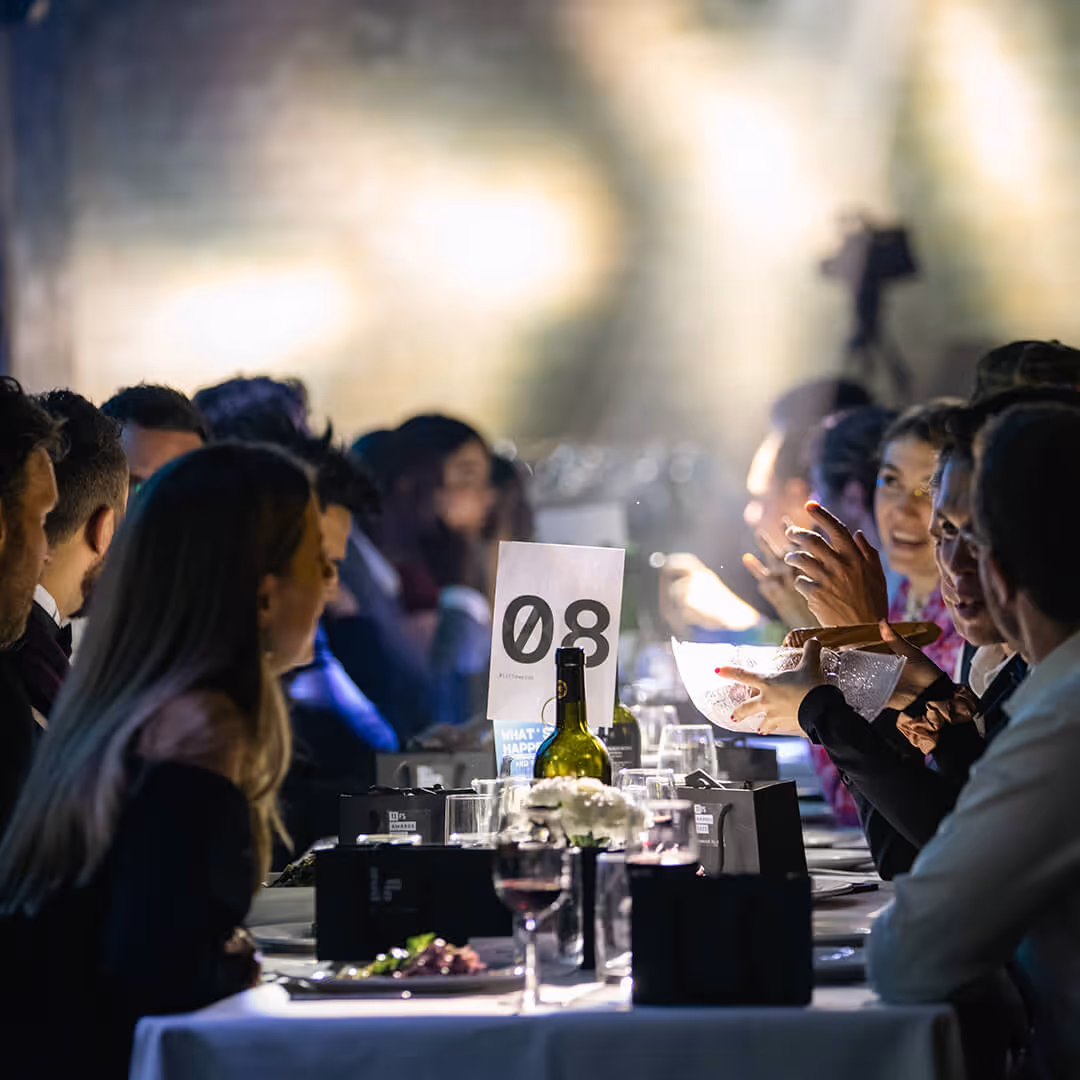 A group of attendees sat down at a table sharing drinks and food