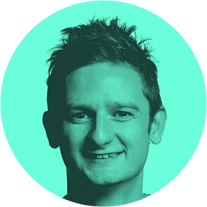 A smiling individual with short, spiky hair is centered in a turquoise circular background.