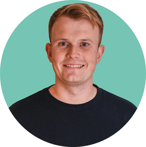 Smiling young man with short light brown hair wearing a black shirt against a green background.