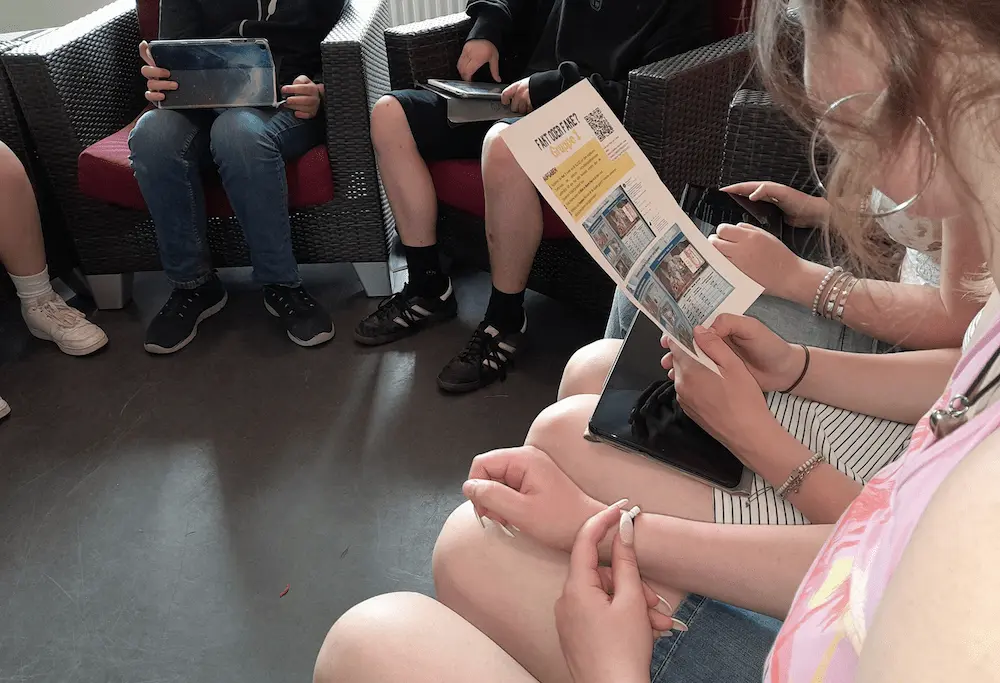 Schüler sitzen im Kreis mit Tablets und Lesematerial
