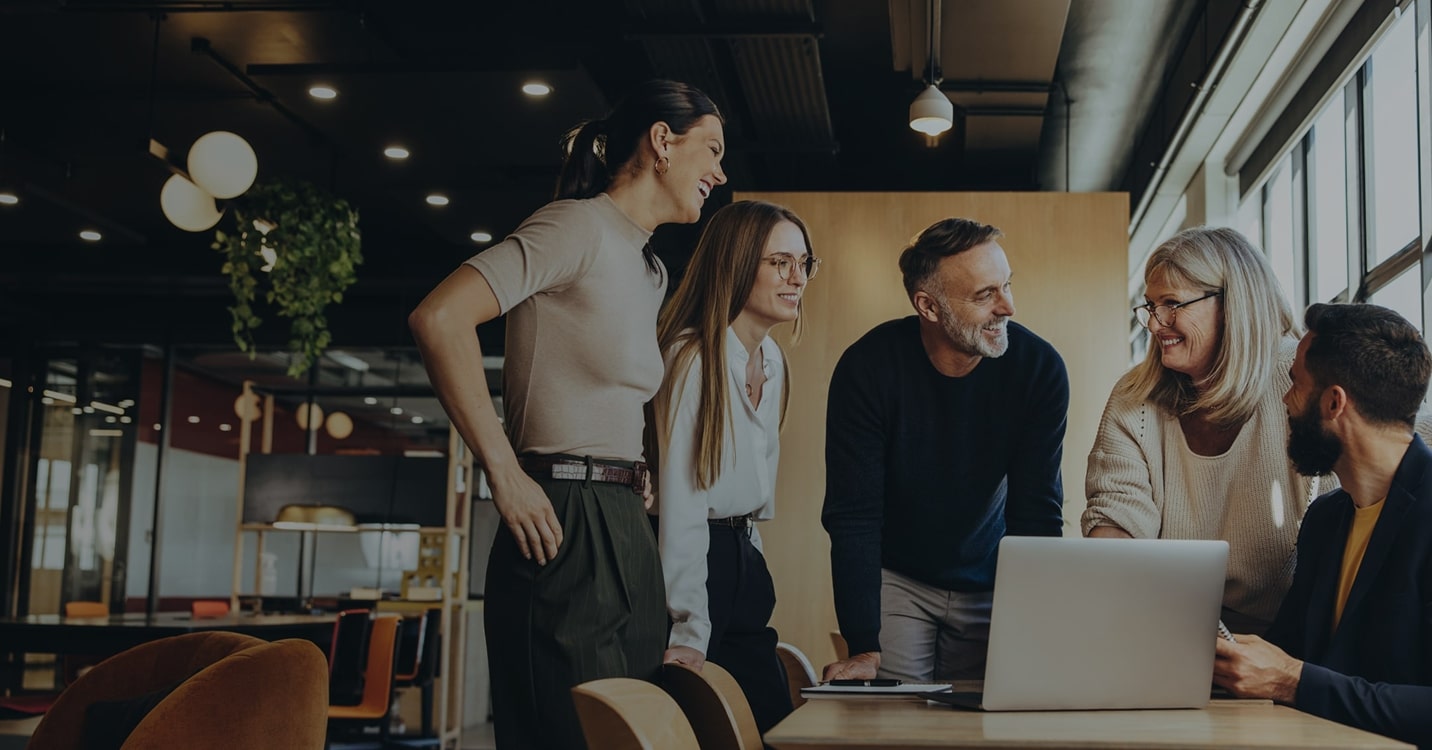 Eine Gruppe von Fachleuten steht um einen Computer herum, arbeitet zusammen und diskutiert Führungskräfte Coaching mit Sharpist.