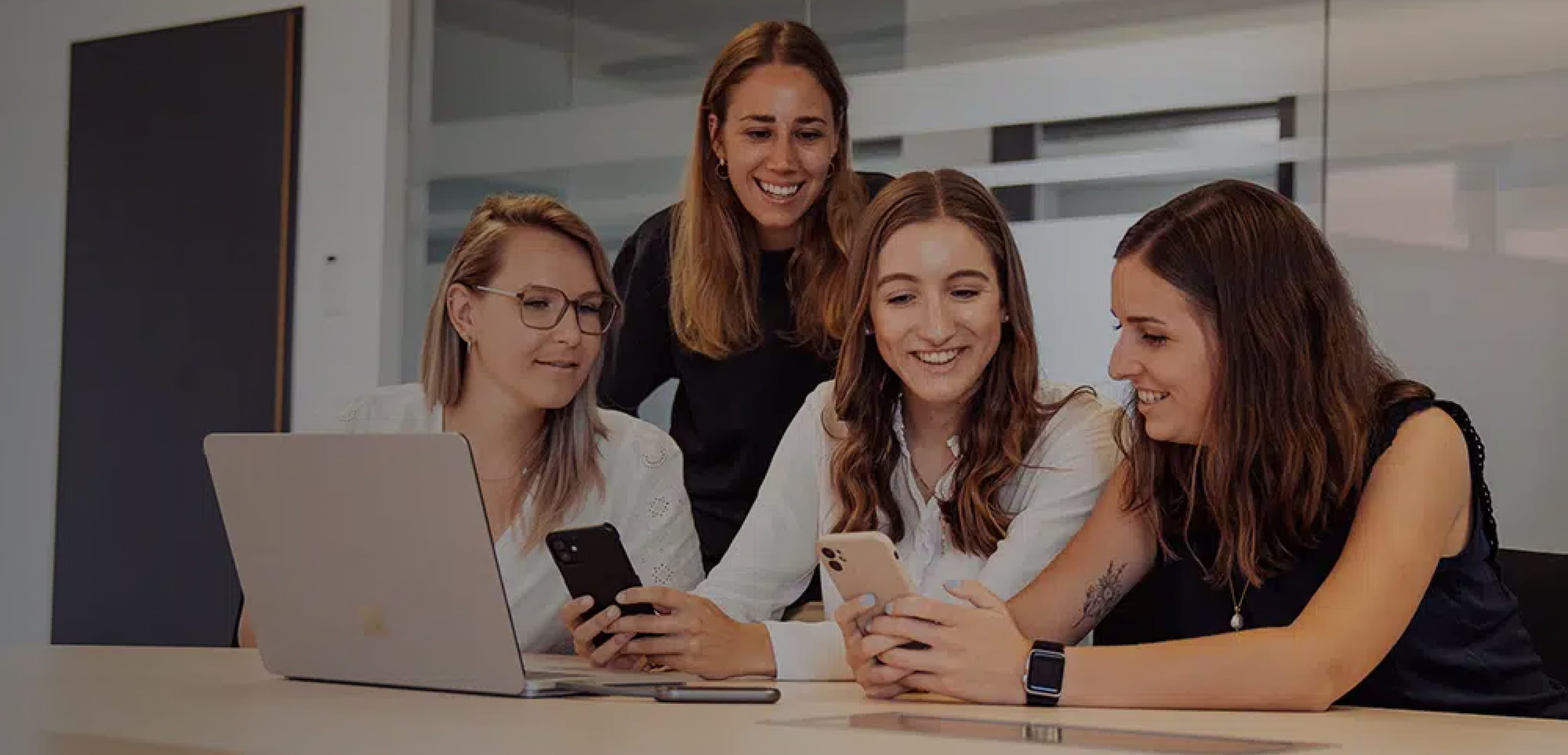 A diverse group of professionals standing around a computer, collaborating and discussing digital coaching solutions with Sharpist.