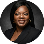 Portrait of a smiling Black woman wearing gold hoop earrings and a black blazer with a dark grey background.