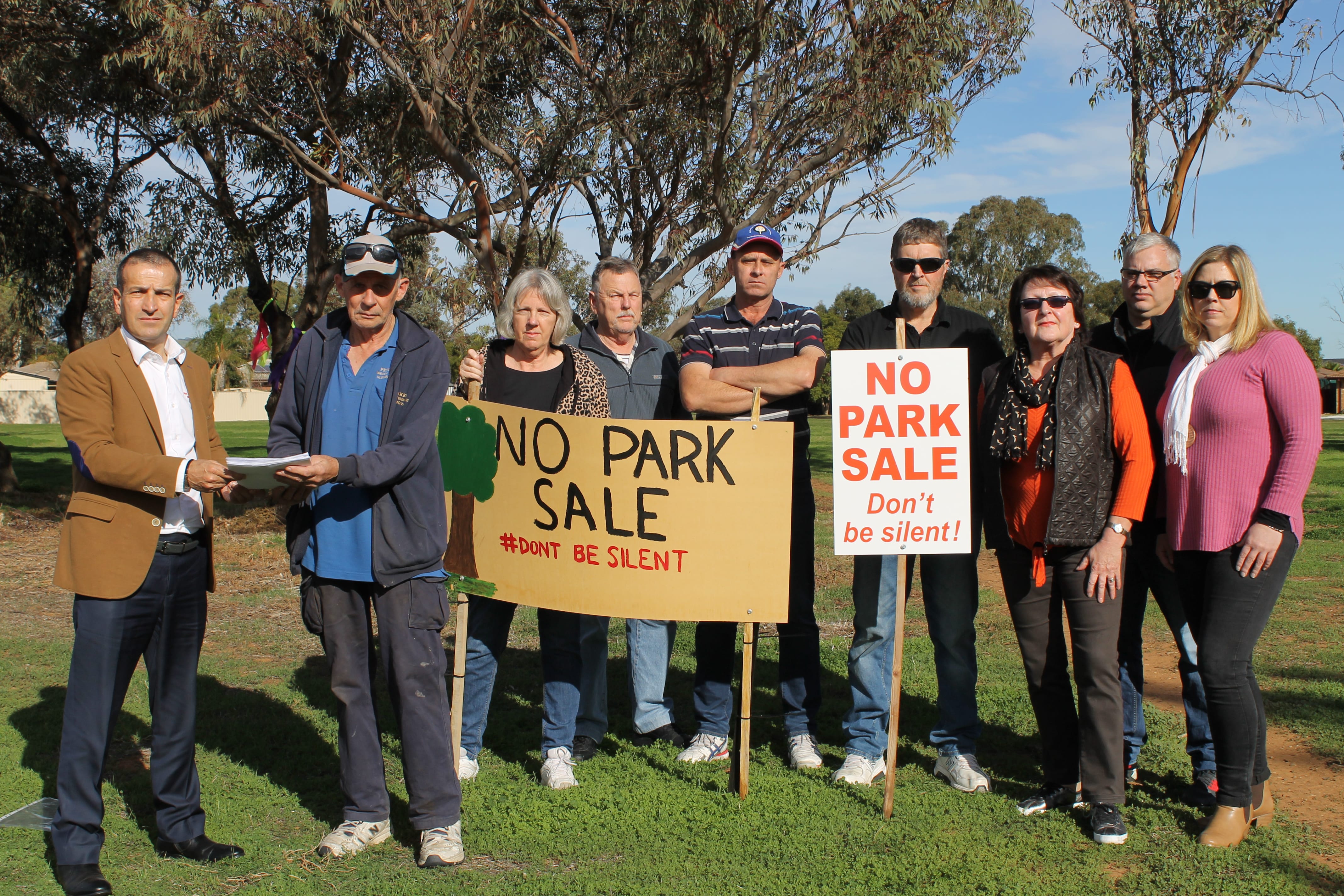Evanston Gardens resident Mr Peter Baker is presenting the petition to local Member of Parliament, Mr Tony Piccolo, who tabled it in State Parliament today, while other aggrieved residents look on. 