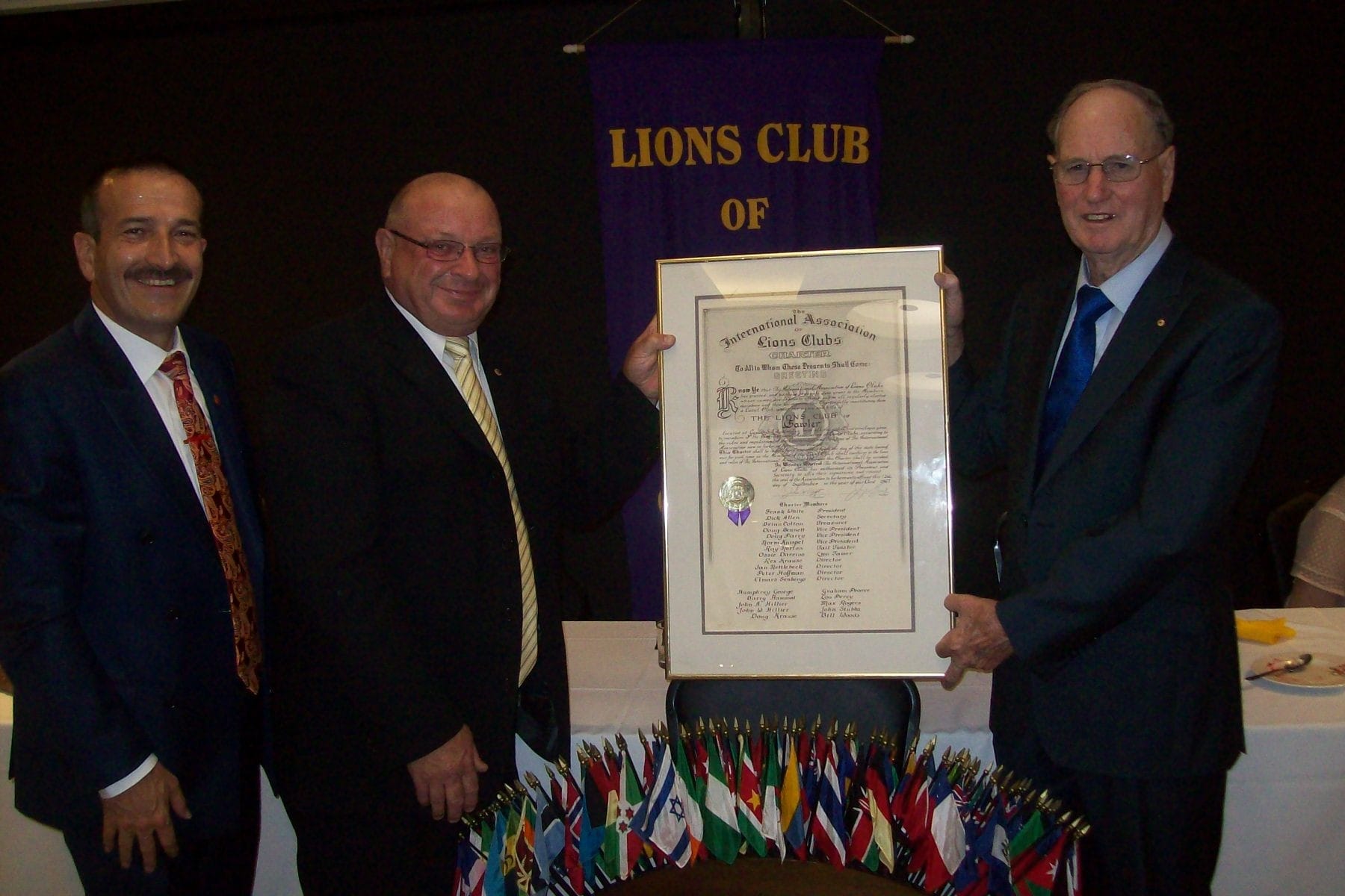 Tony Piccolo MP with current President Ray Brussow and charter member Humphrey George (on far right) holding the original charter at the birthday celebrations. 