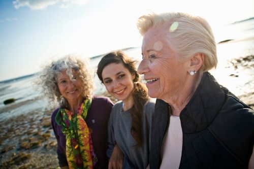 three generations of women smiling on the beach