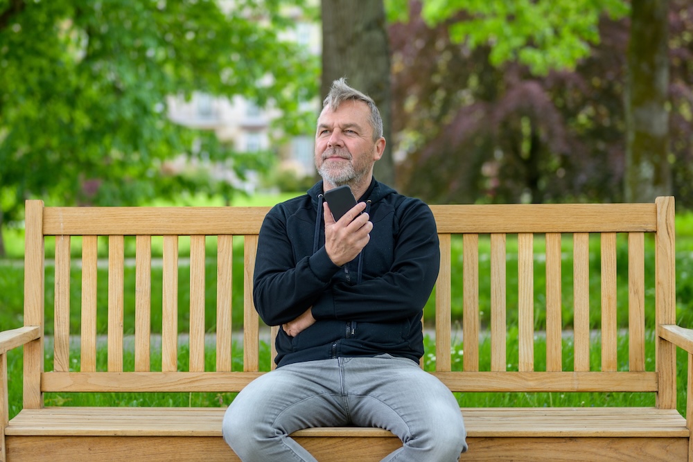 man sitting on phone on park bench