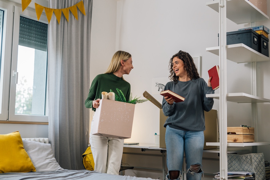 two college aged women taking while unpacking boxes