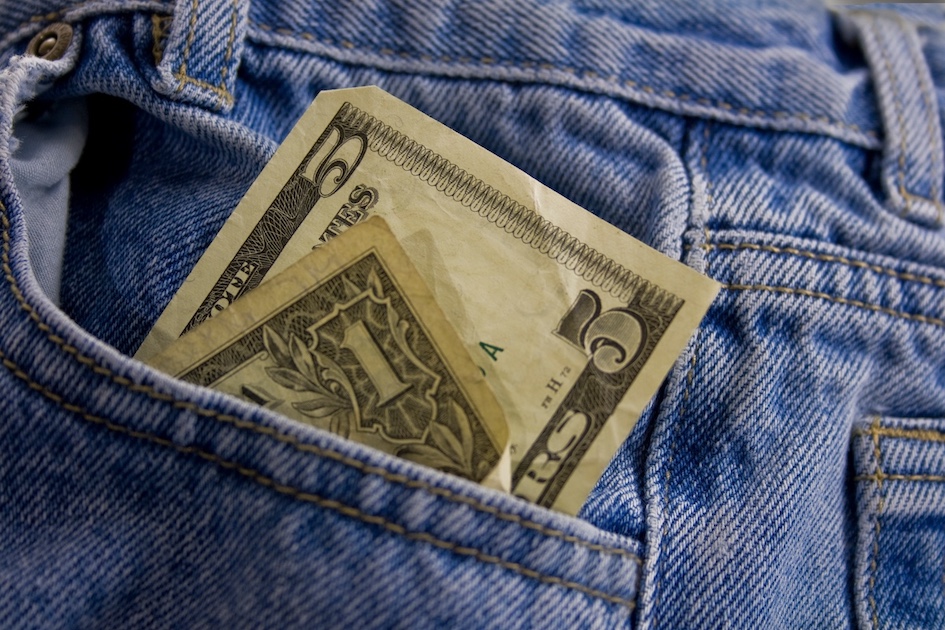 Blue jeans pocket with one dollar and five dollar bills