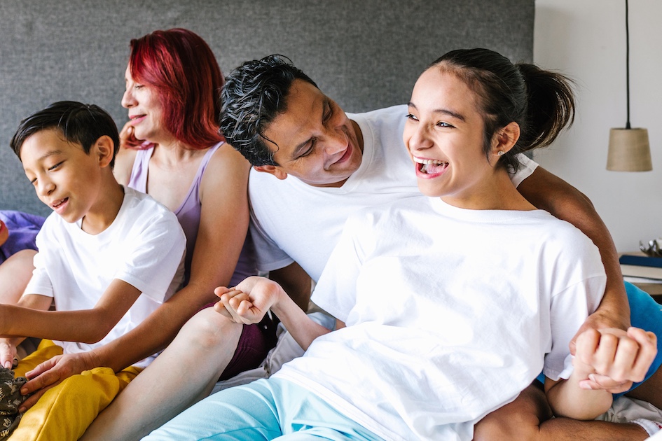 blind hispanic young adult female laughing with her father, brother and mother