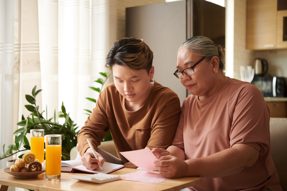 Asian mother and son reviewing documents at kitchen table