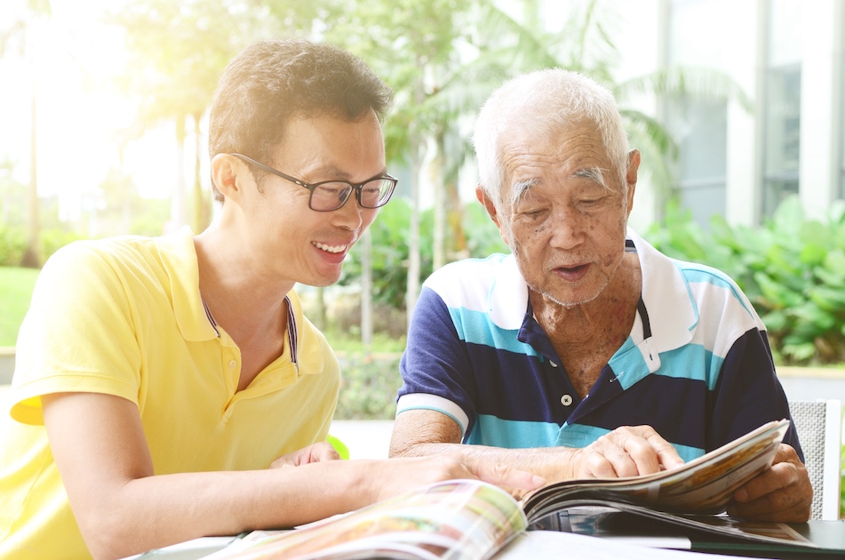 elderly asian man with his mid-age son smiling and talking