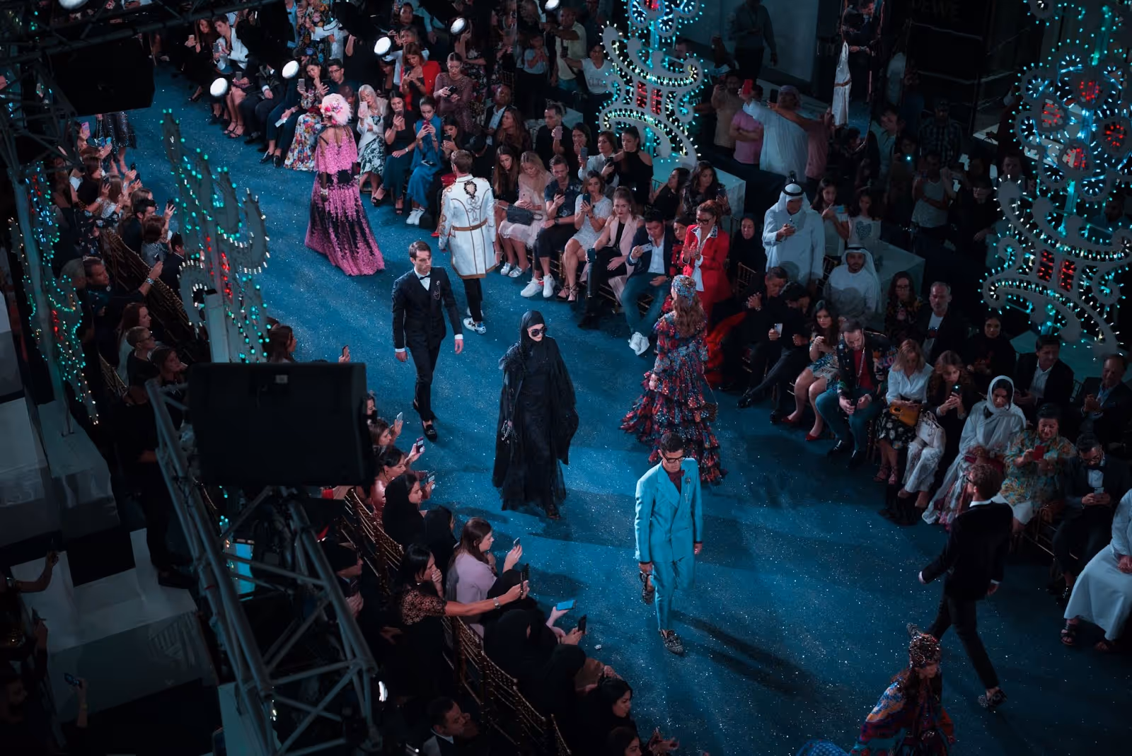 Runway show with male models in formalwear and female models in bohemian dresses