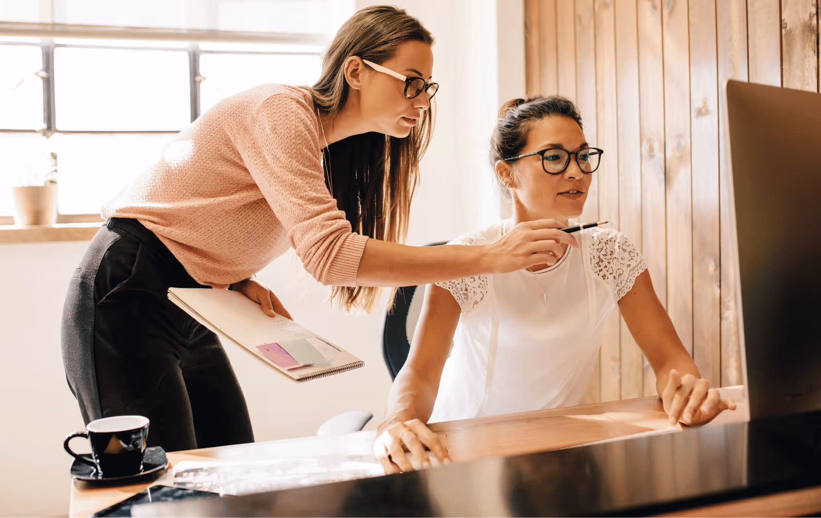 Fashion brand team reviewing wholesale pricing strategy and retailer performance data on screen, collaborating on retail partnership optimization and pricing alignment.