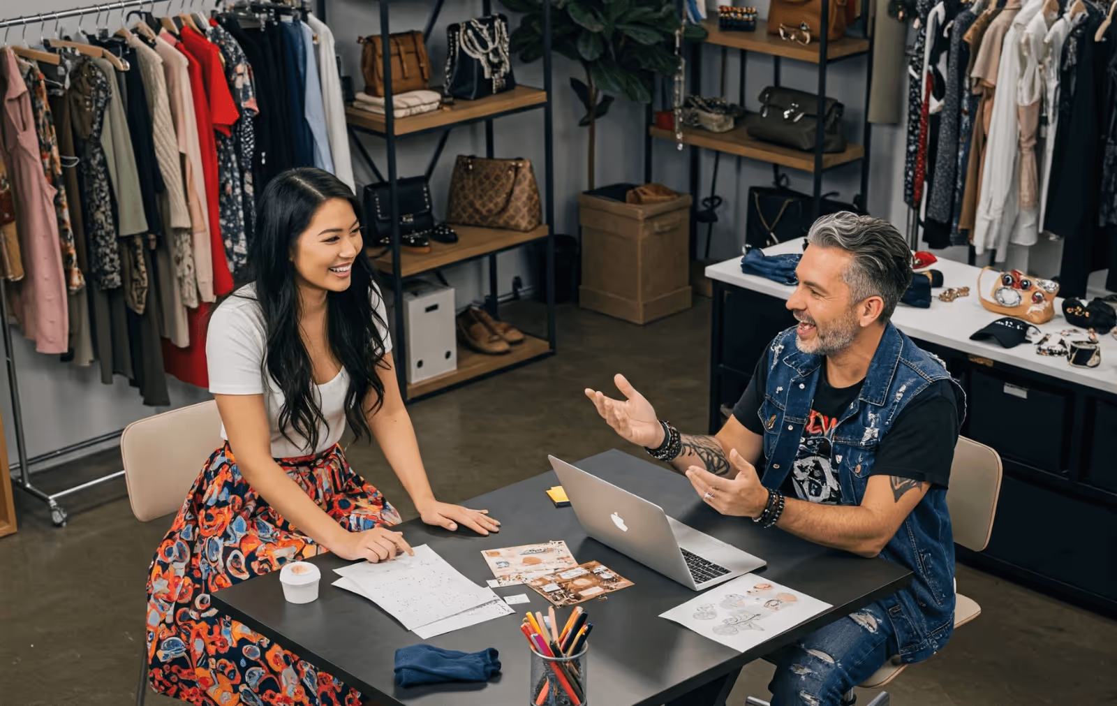 A brand rep sat at a table pitching a collection to a fashion buyer in a showroom