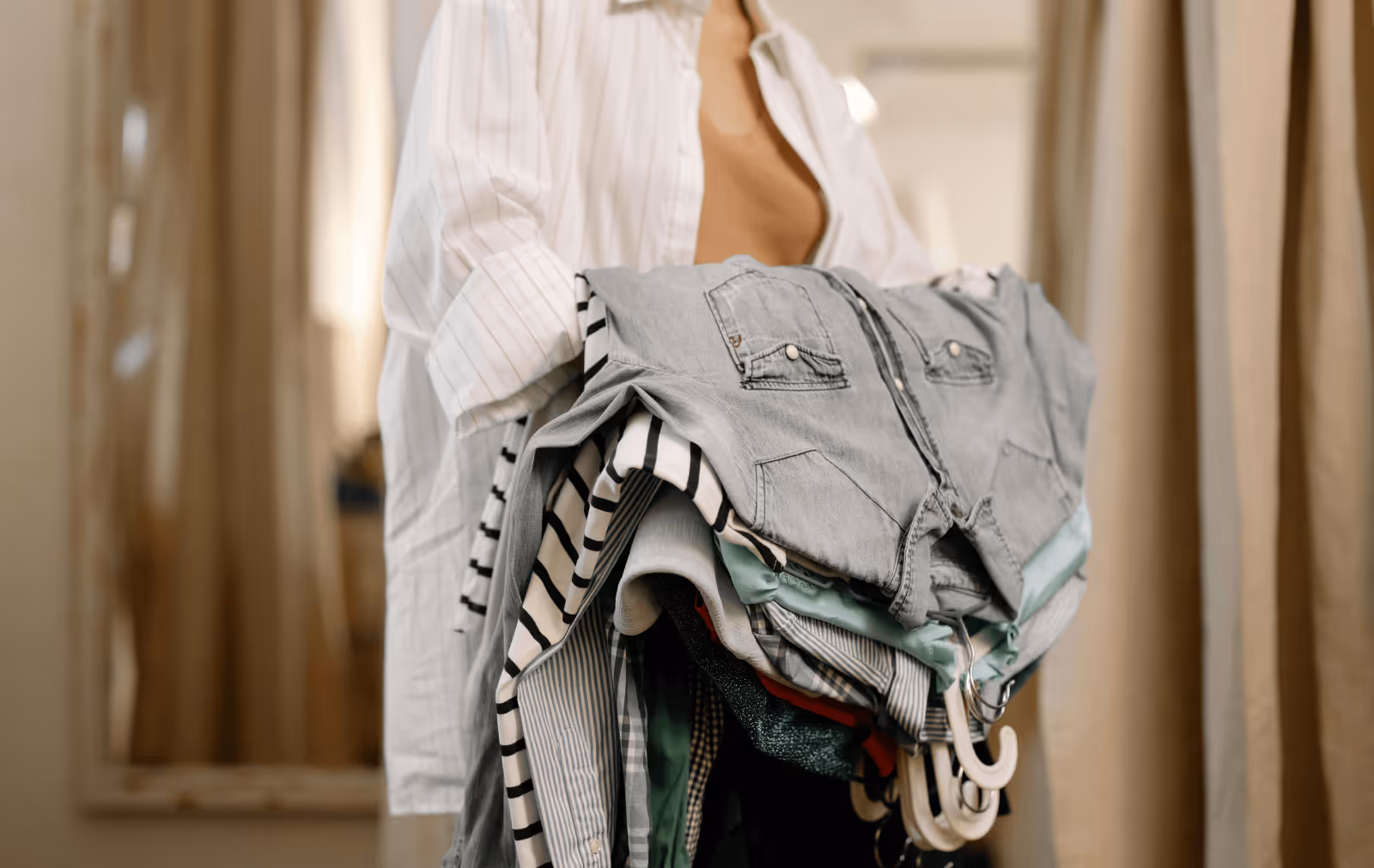 woman in white shirt holding clothes on hangers over her arm