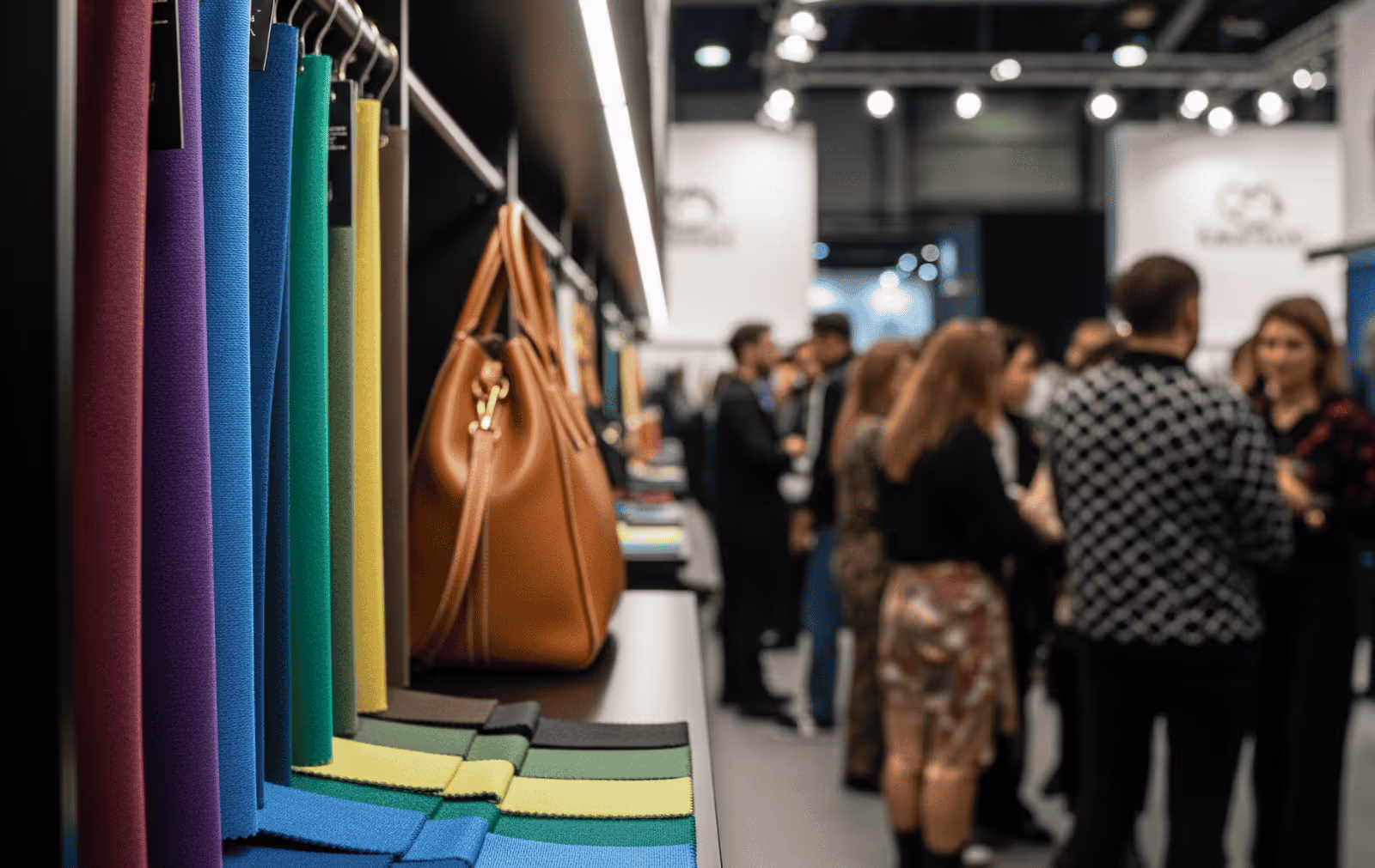 Coloured material samples and brown leather handbag on display at fashion tradeshow