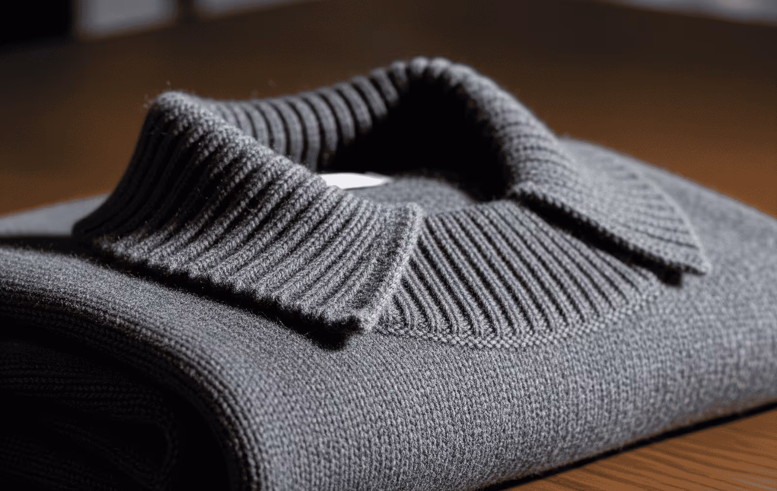 Luxury grey sweater with collar folded on wooden table