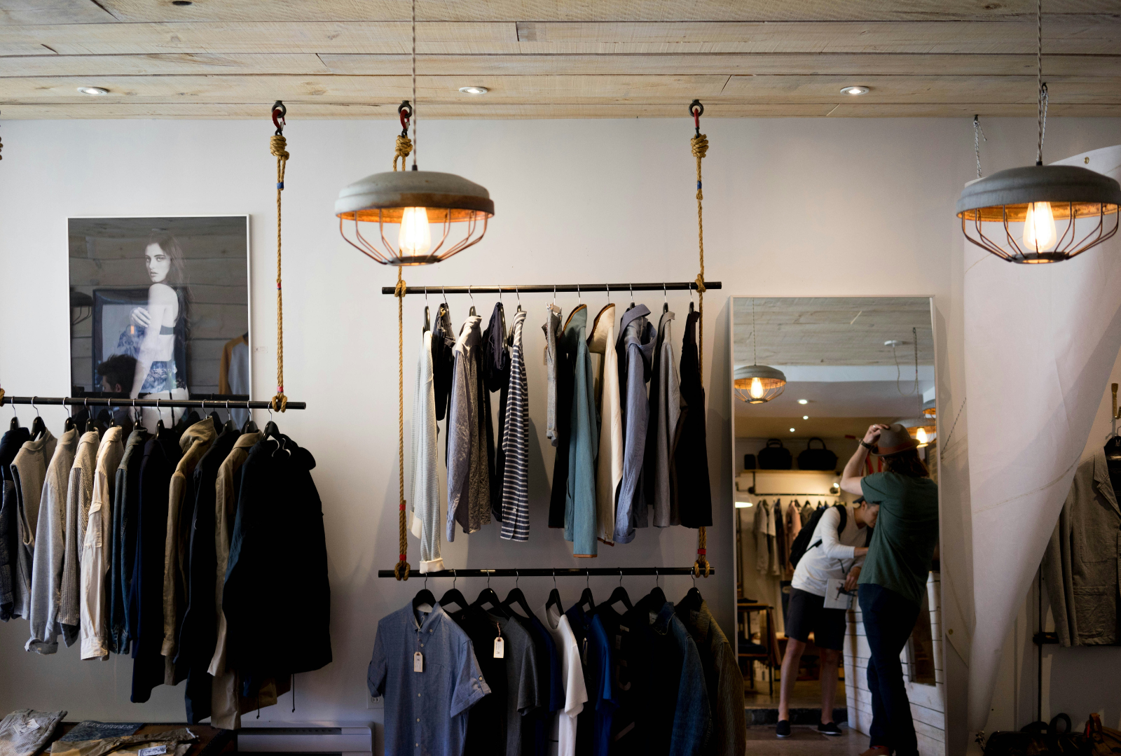 A fashion showroom with with a variety of clothing on racks and people interacting with each other.