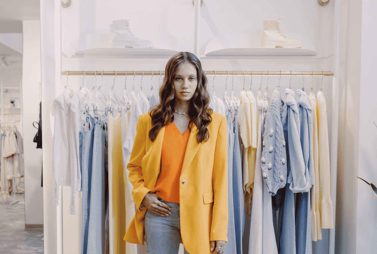 A fashionable woman standing in front of a rack of colorful clothes